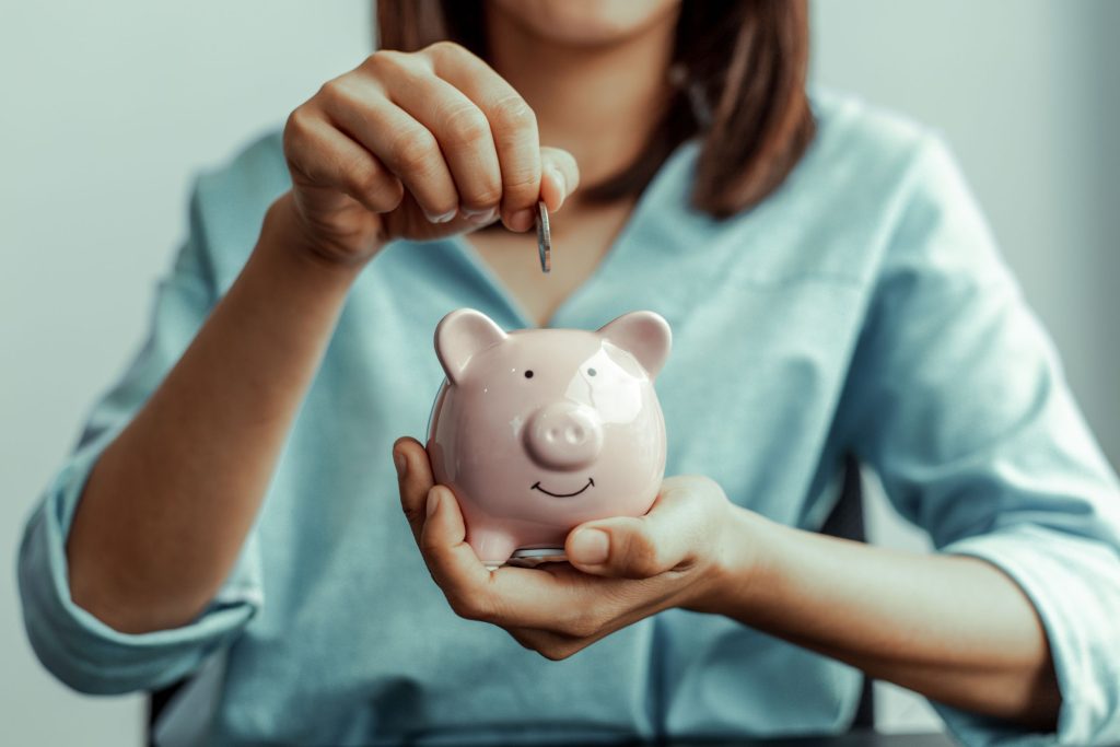 Woman putting a coin in a piggy bank