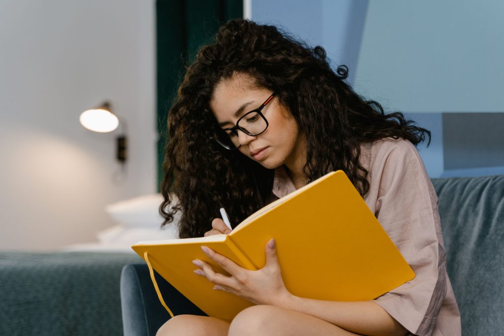 Woman journaling in a yellow notebook